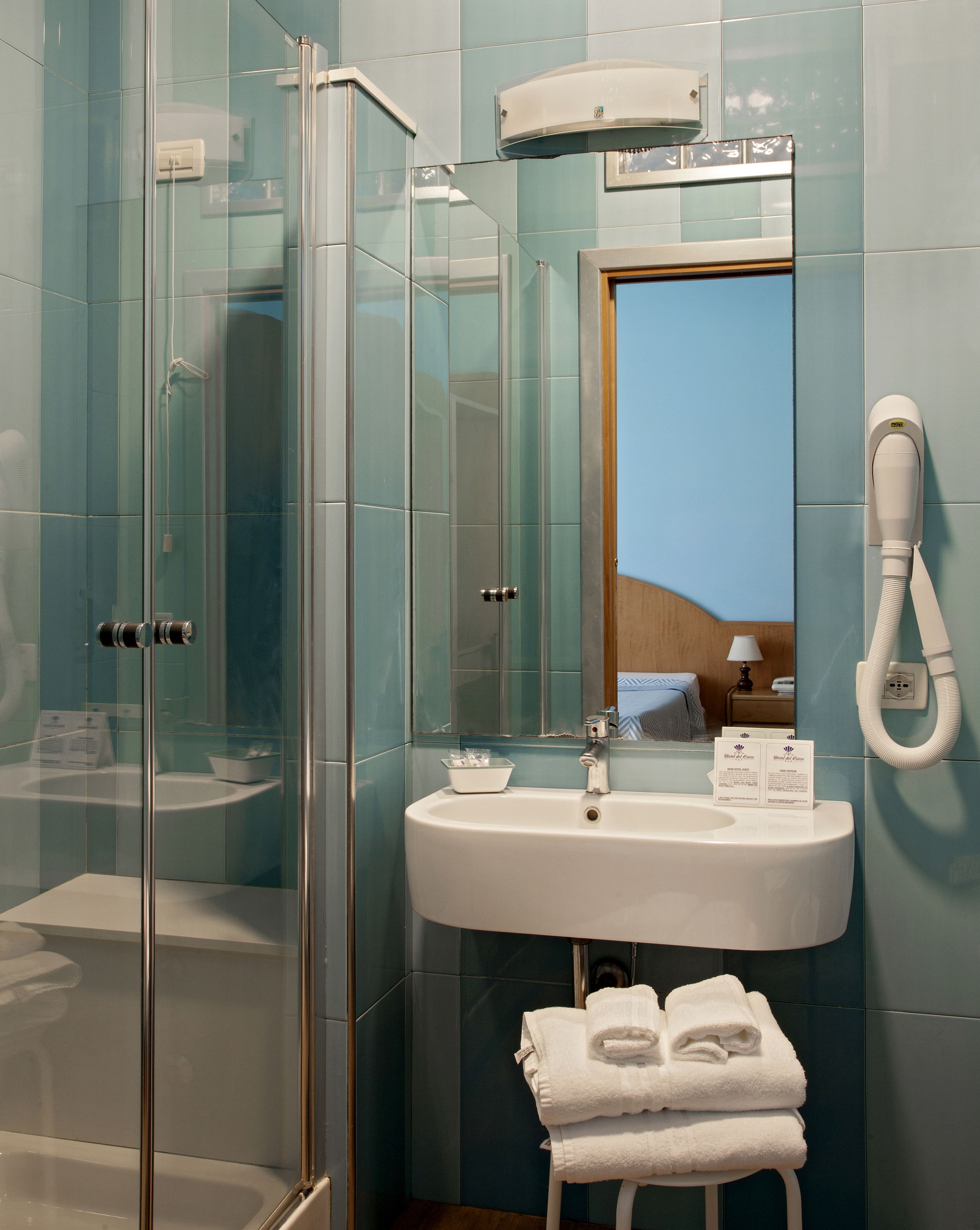 A bathroom with a glass shower enclosure, a sink with a mirror, and a towel rack.