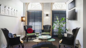 A modern interior with a seating area featuring two black chairs, a round table, and a potted plant.