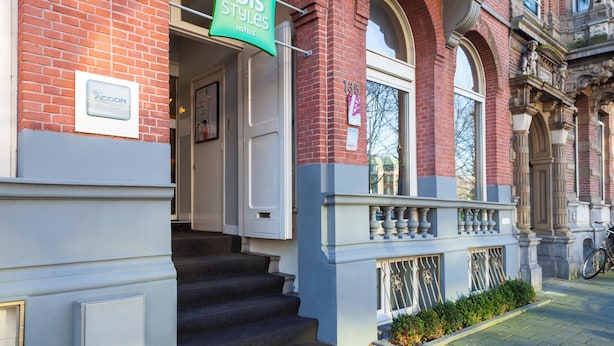 A hotel entrance with a green sign reading "ibis Styles Amsterdam City Hotels".