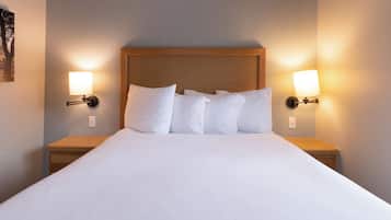 A neatly made bed with white linens, two bedside tables with lamps, and a wooden headboard.