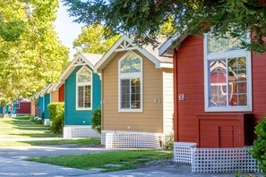 A row of colorful, single-story houses with numbered windows, white picket fences, and well-maintained lawns. - RiverPointe Napa Valley Resort (Napa)