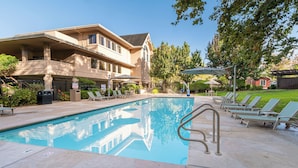 A pool area with lounge chairs, a pool, and a building with a balcony. - RiverPointe Napa Valley Resort (Napa)