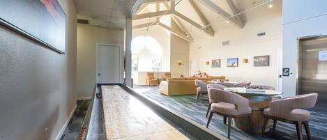 A spacious hotel lobby with a shuffleboard court, comfortable seating, and artwork on the walls.