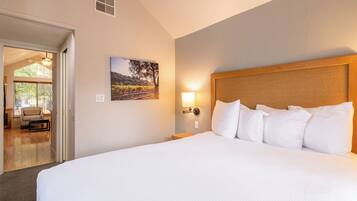A hotel room with a large bed, a headboard, a bedside lamp, and a picture on the wall.