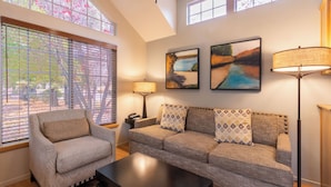 A living room with a sofa, armchair, and coffee table. There are two paintings on the wall and a floor lamp. - RiverPointe Napa Valley Resort (Napa)