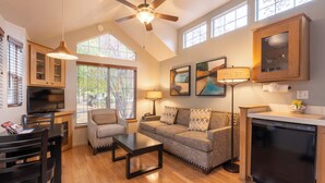 A spacious living room with a ceiling fan, wooden flooring, a sofa, a coffee table, and a television. - RiverPointe Napa Valley Resort (Napa)
