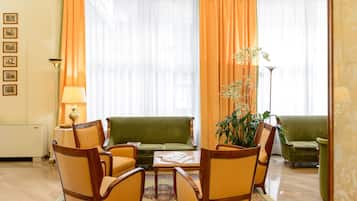 Ein Wohnzimmer mit einem grünen Sofa, gelben Sessel, einem Couchtisch und einer Topfpflanze.