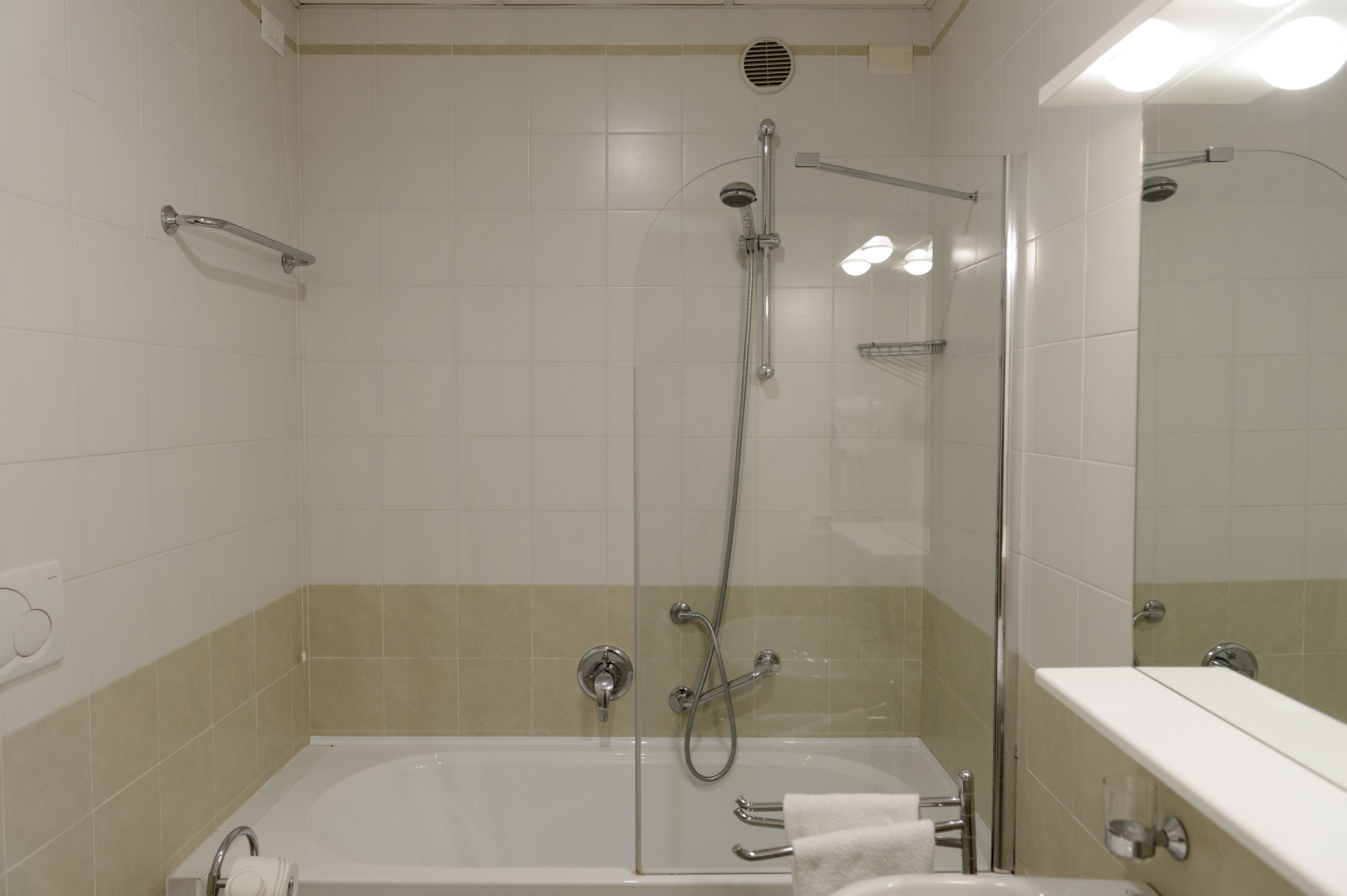 A modern bathroom with a glass-enclosed shower, a separate bathtub, and a vanity with a mirror.