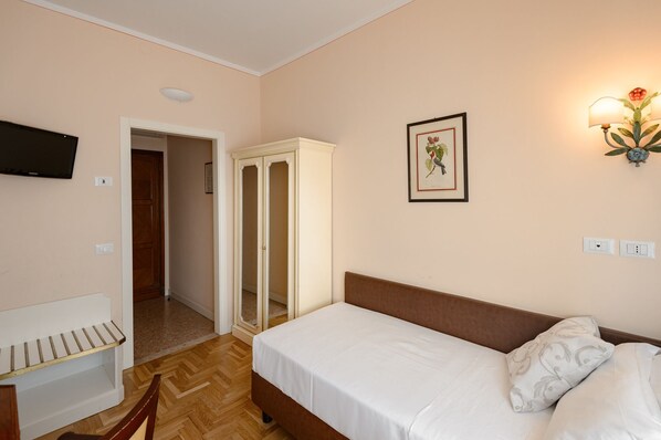 A bedroom with a bed, a wardrobe, a television, and a wall-mounted light fixture. - Hotel Continental (Treviso)