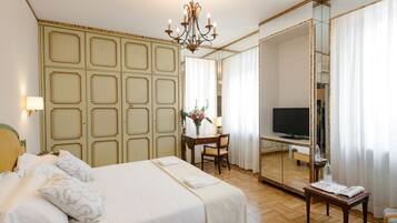 Une chambre d’hôtel avec un grand lit, un bureau avec une chaise, une télévision et un miroir.