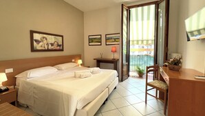 A hotel room with a large bed, a desk, a chair, a TV, and a balcony with a view. - Hotel Leopolda (Florence)
