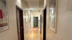 A hallway with wooden flooring, framed pictures on the walls, and doors on both sides. - Hotel Leopolda (Florence)