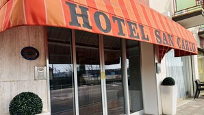 The exterior of Hotel San Carlos with a large sign, a glass entrance, and a small potted plant. - Hotel San Carlo (Mestre)