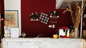 A reception area with a marble counter, two red bar stools, a menu board, and decorative items on the wall. - Hotel San Carlo (Mestre)