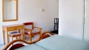 Una habitación con cama, escritorio, silla y espejo.