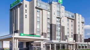 Un hotel moderno con una entrada destacada, varios pisos y un letrero verde que indica el nombre.