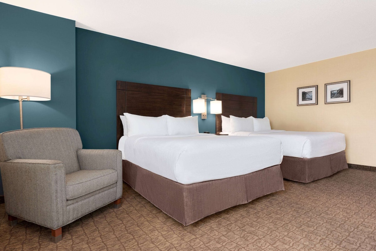 Une chambre d’hôtel avec un grand lit, une chaise et deux lampes fixées au mur.
