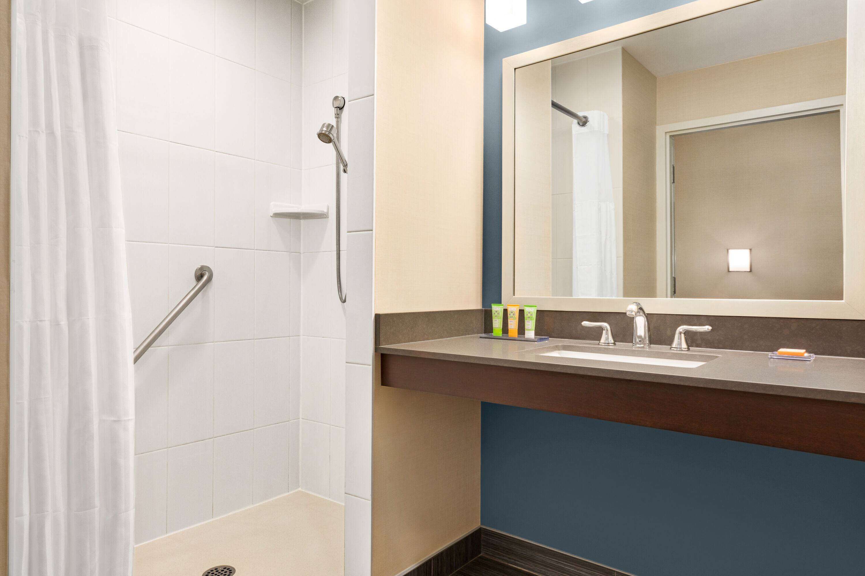 A bathroom with a shower, a sink, and a mirror.