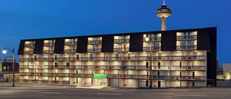 A multi-story hotel with a prominent tower entrance and a tower in the background.