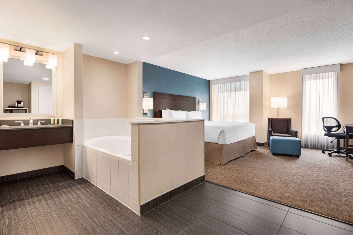 Ein Hotelzimmer mit eigenem Bad, einem Bett, einem Schreibtisch und einem Sessel.