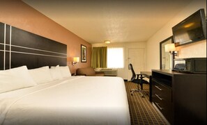 A hotel room with a large bed, a desk with a chair, a television, and a microwave.