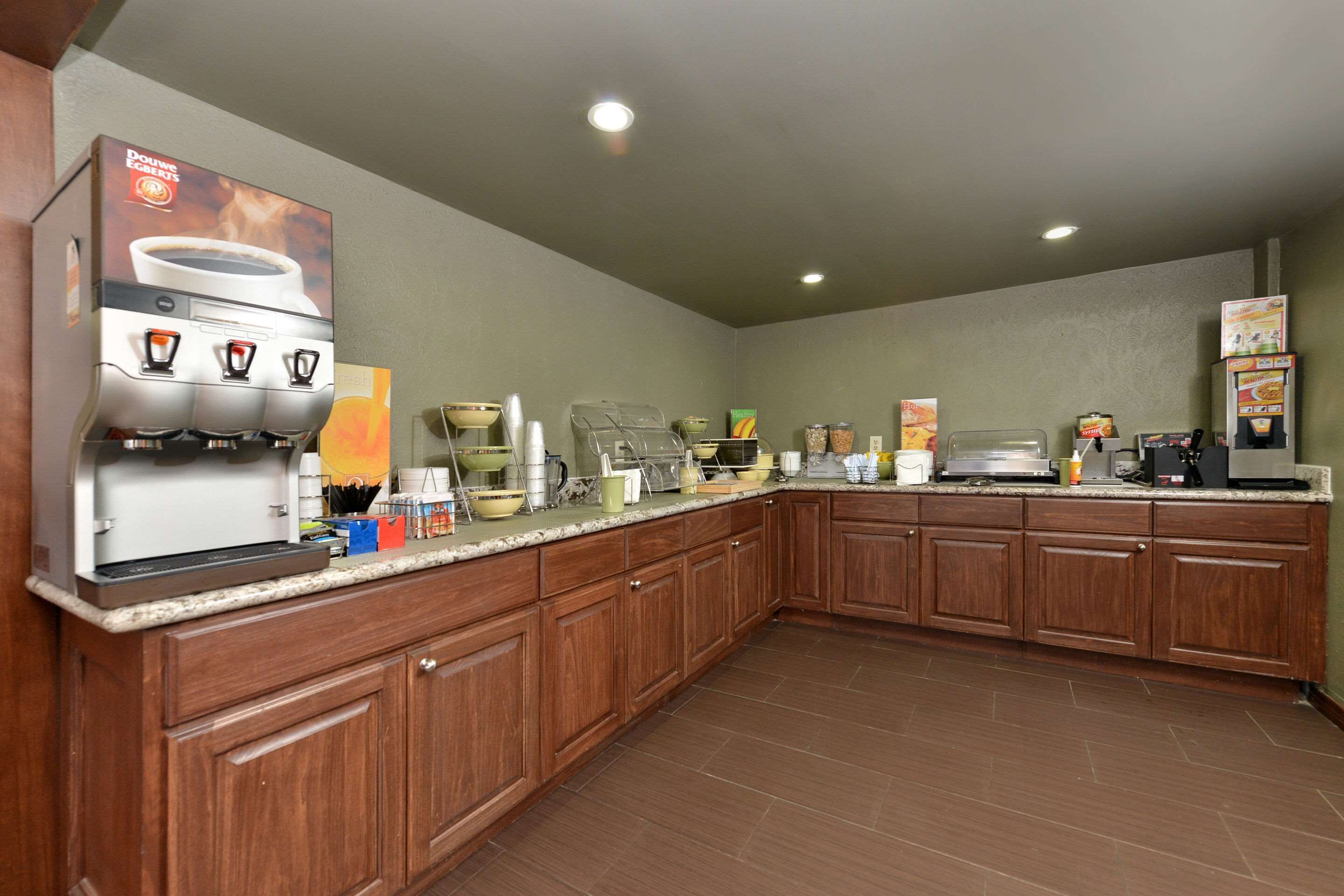 A commercial kitchen with a coffee machine, various food preparation stations, and storage cabinets.