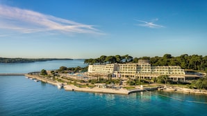 A coastal hotel with a pool, outdoor seating, and a view of the sea. - Isabella Island Hotel & Villas, Valamar Collection (Porec)