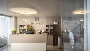A modern spa reception area with a minimalist design, featuring a reception desk, shelves with spa products, and a large wall-mounted sign. - Isabella Island Hotel & Villas, Valamar Collection (Porec)