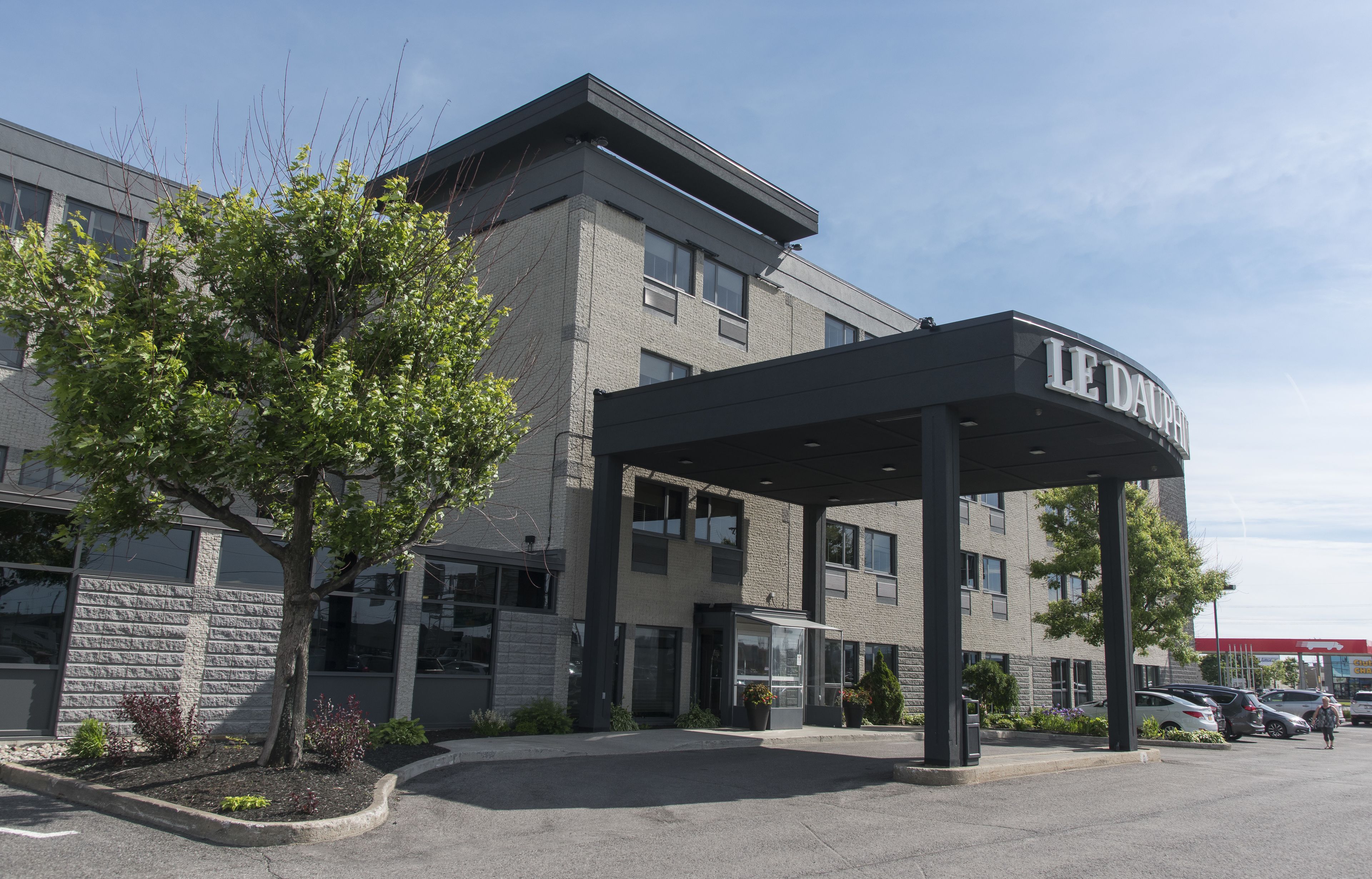 A LE DAUPH hotel with a covered entrance, parking lot, and a building with a brick facade.