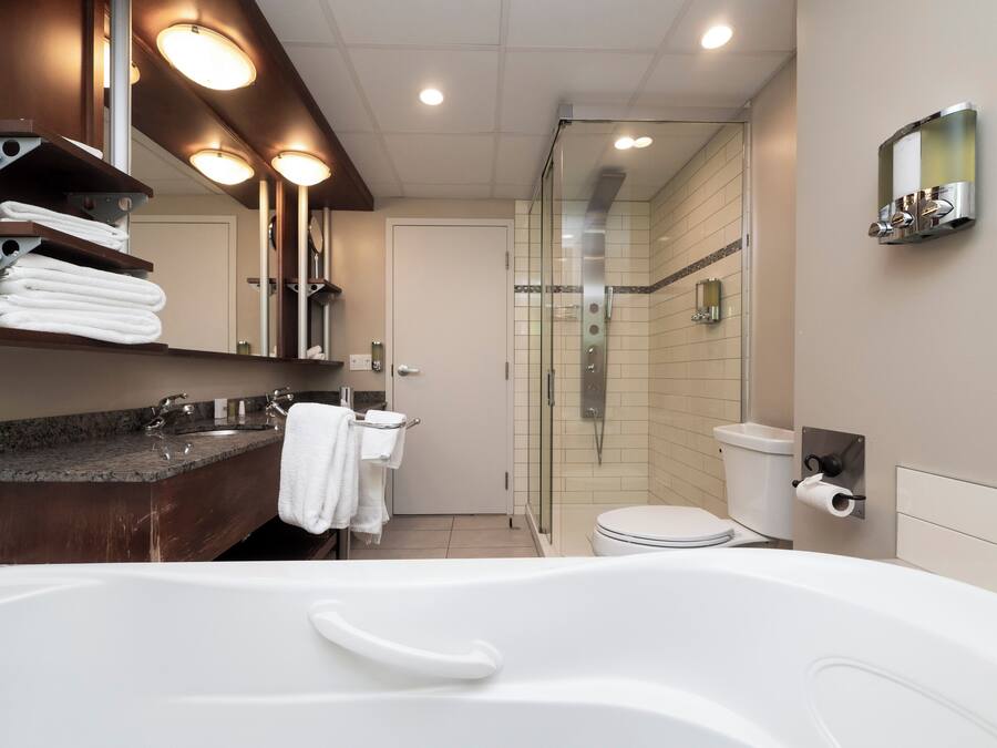 Un bagno moderno con una vasca da bagno ampia, una cabina doccia in vetro e un water.