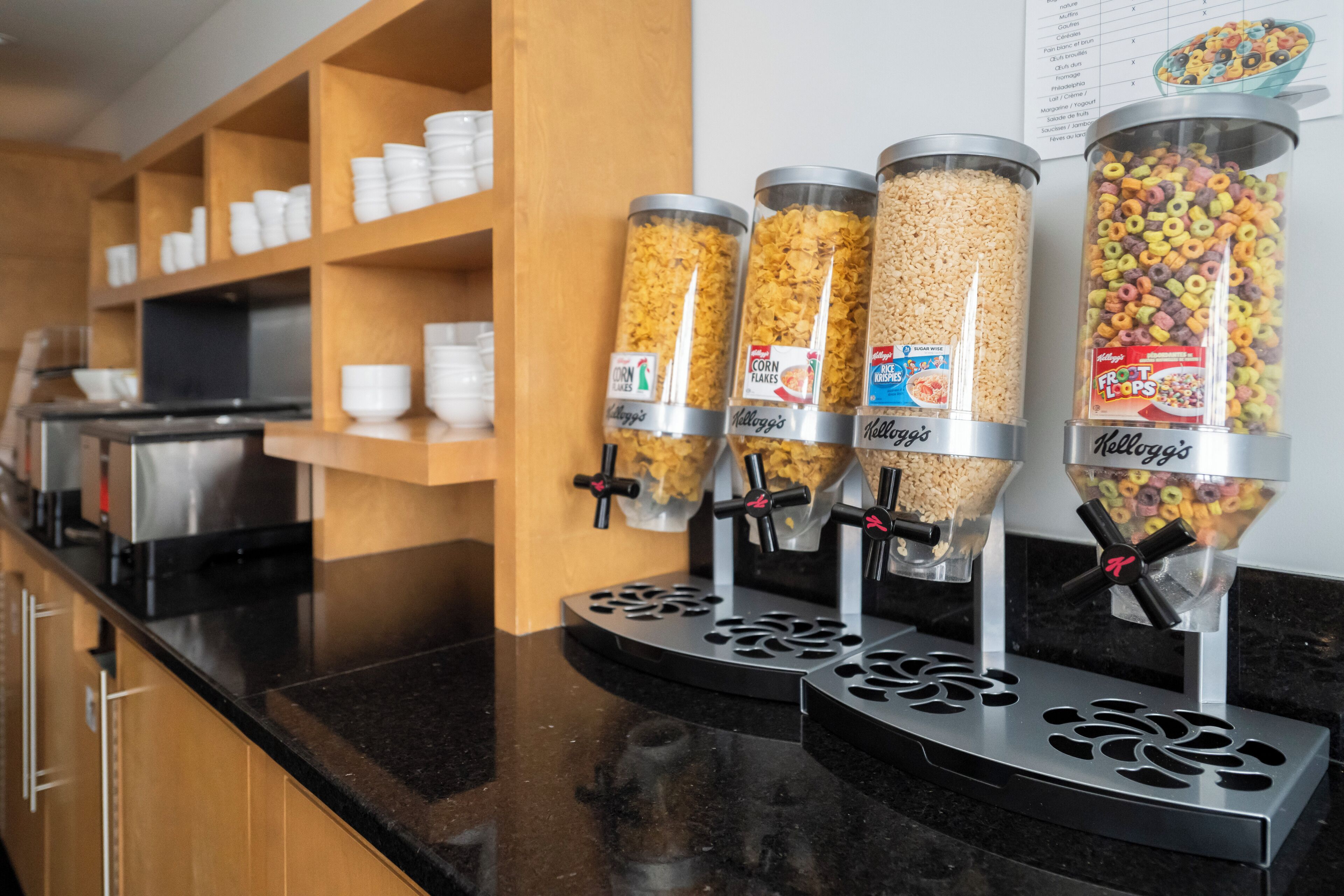 Zona de bufé con dispensadores de cereales, incluyendo Kellogg's Corn Flakes, Rice Krispies y Fruity Pebbles.