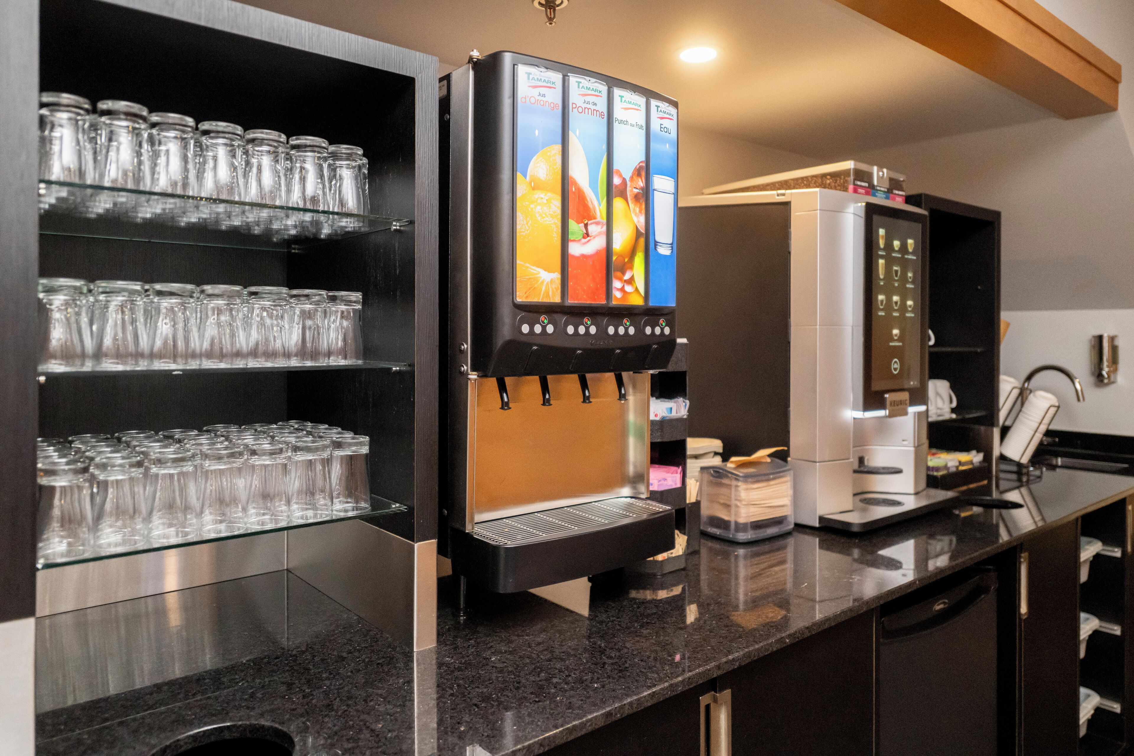 A beverage dispenser with multiple drink options, a glassware rack, and a coffee machine.