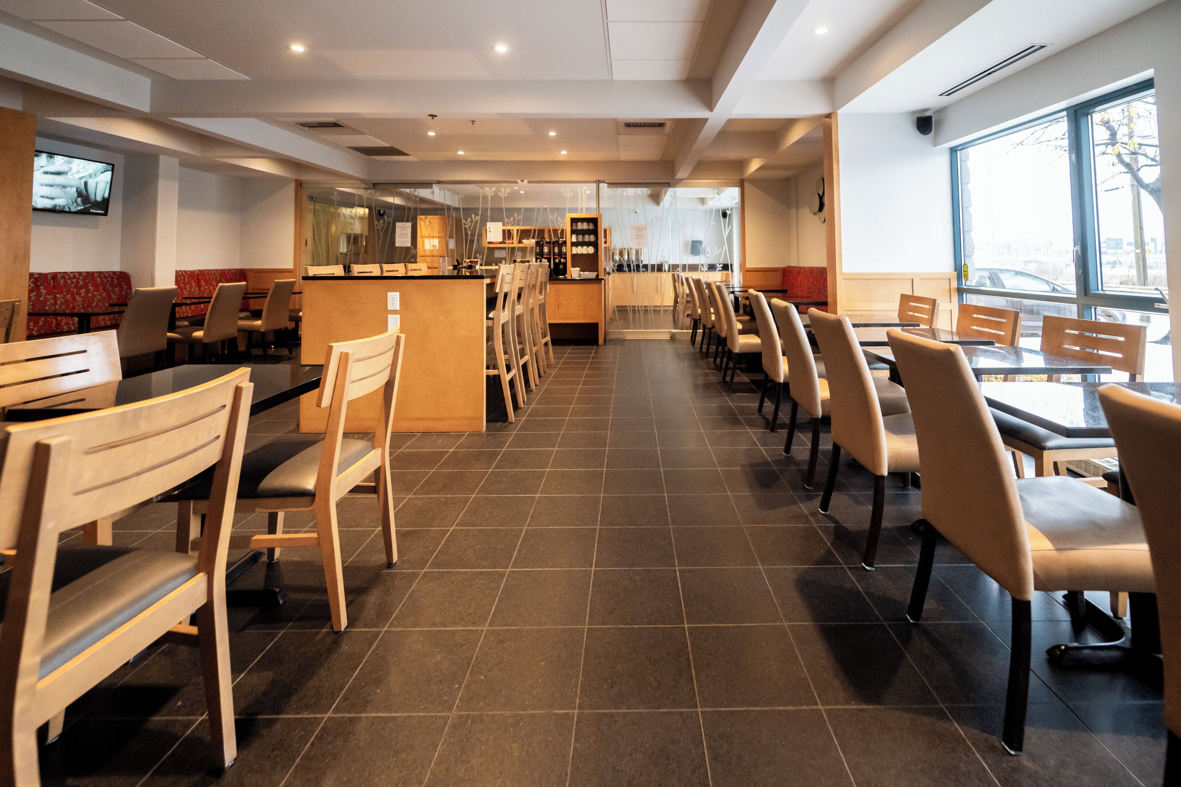 Ein modernes Restaurant-Interieur mit einer langen Theke, Sitzgelegenheiten in Boxen und einer hohen Decke.