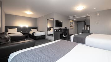 Une chambre d’hôtel avec deux lits, un canapé, un bureau, une télévision et un miroir.