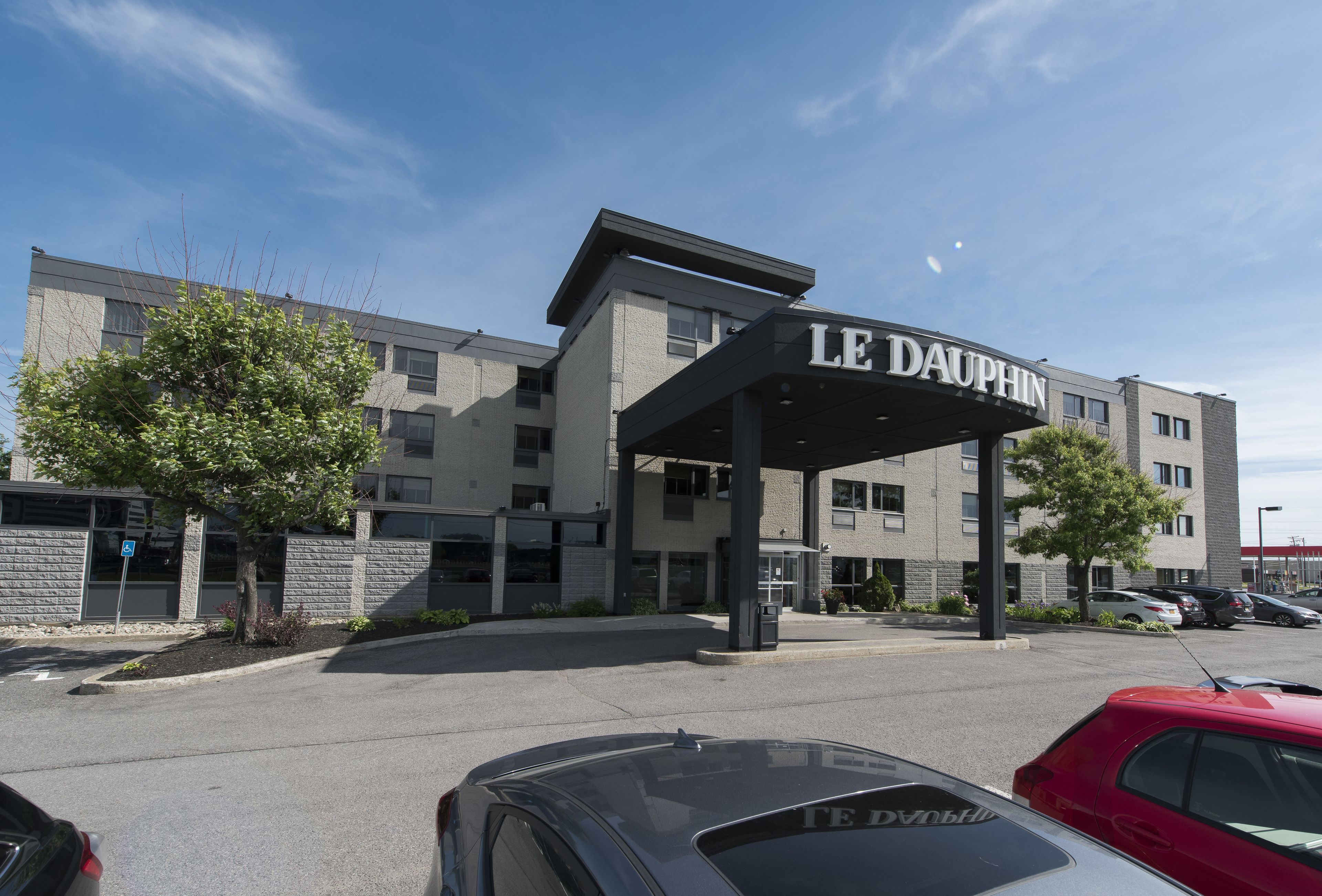 A LE DAUPHIN hotel with a covered entrance, parking lot, and adjacent buildings.