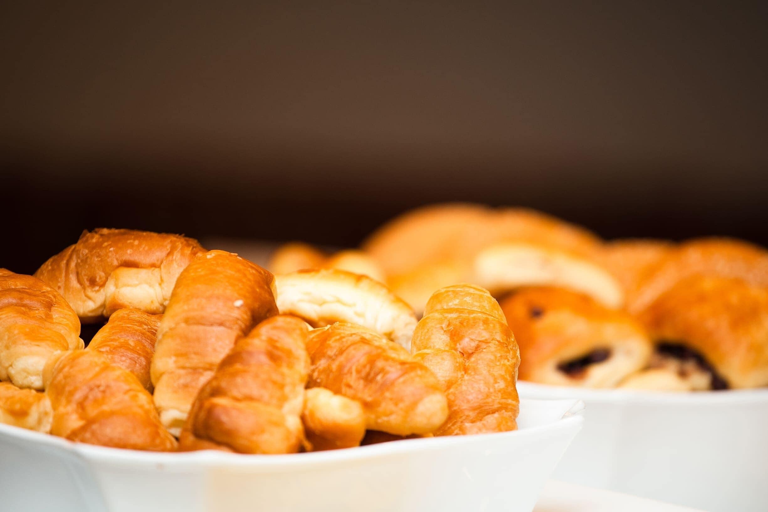 Variedad de productos horneados, incluyendo croissants y otras vieneserías, dispuestos en un cuenco blanco.