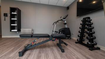 A gym with a bench, elliptical, and dumbbells.