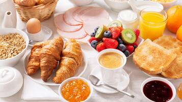 A breakfast setting with croissants, toast, fruit, and beverages.