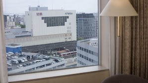 Une chambre d’hôtel avec vue sur le paysage urbain, comprenant un immeuble avec une enseigne et un espace de stationnement.