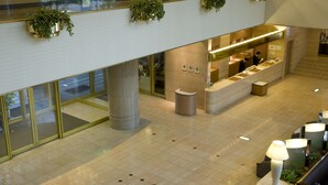 Un hall d’hôtel moderne comprenant un comptoir d’accueil, un espace salon et des plantes décoratives.