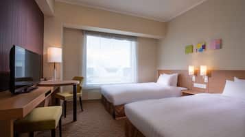 A hotel room with two beds, a desk with a chair, a television, and a window with curtains.