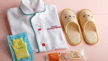A neatly folded white shirt with green trim and red buttons, a pair of beige slippers with a bear face, a body sponge, and a packet of bear-themed body scrub.