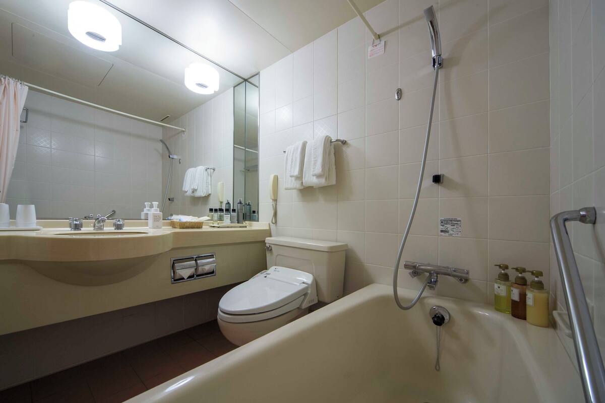 Een badkamer met een bad, toilet, wastafel en een spiegel.