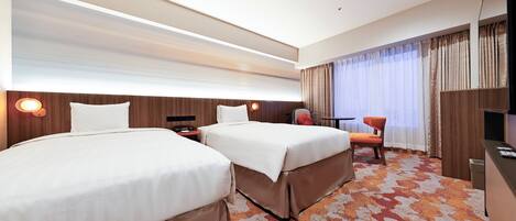 Ein Hotelzimmer mit zwei Betten, einem Schreibtisch, einem Stuhl und einem Fernseher.