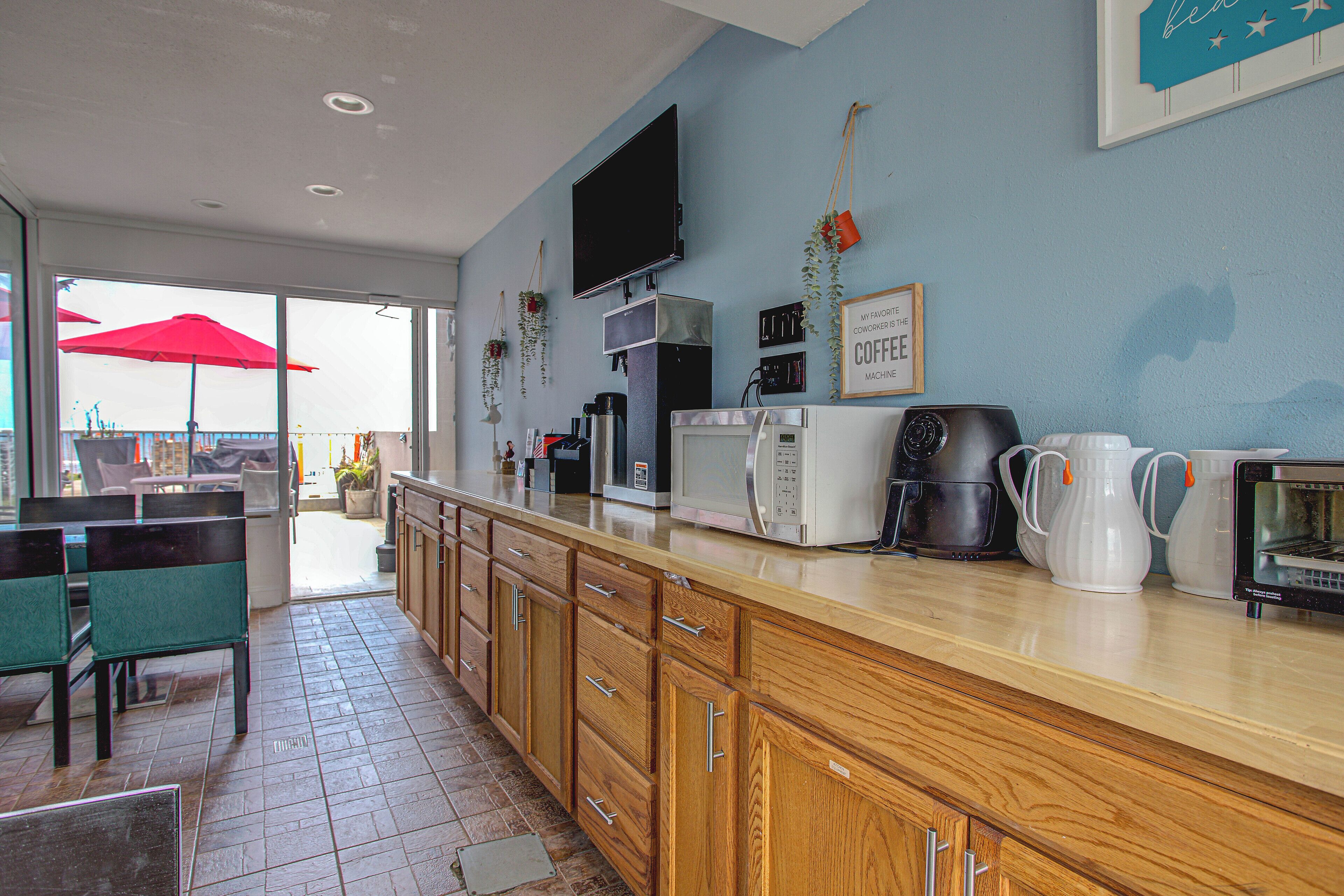 A kitchen with wooden cabinets, a coffee machine, a microwave, and a TV on the wall.
