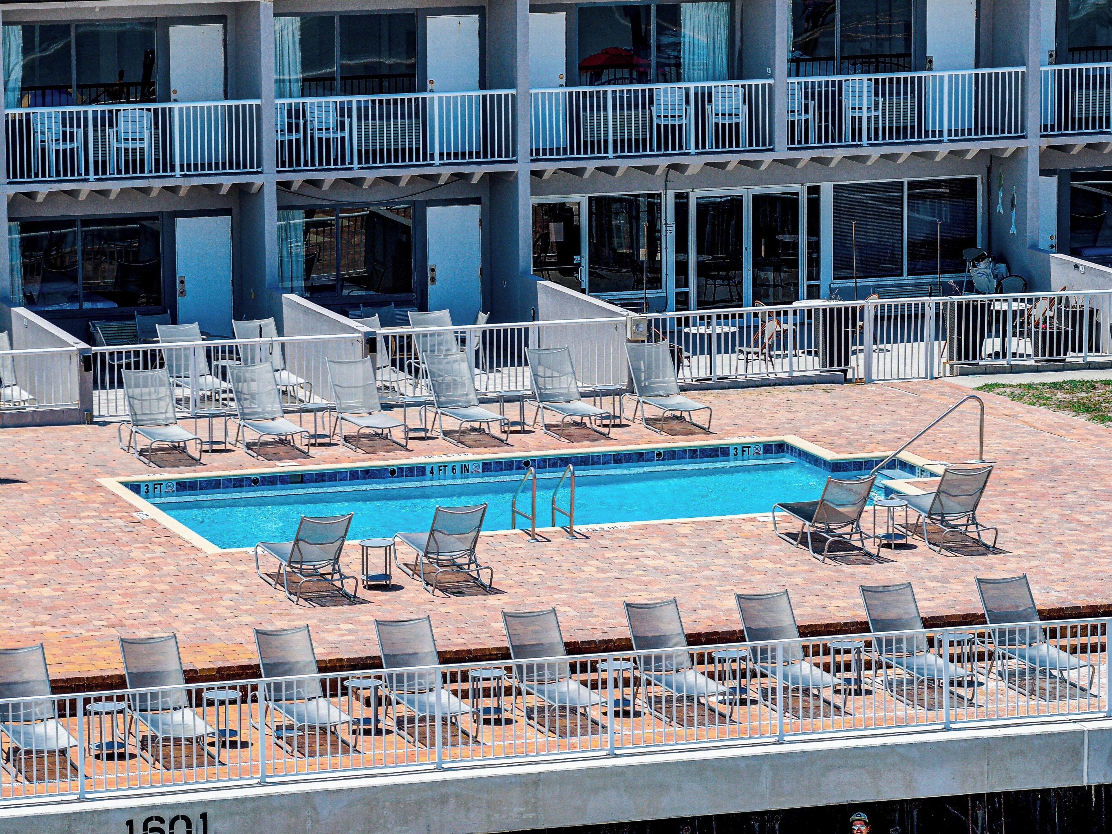 Piscina no terraço com várias espreguiçadeiras e uma mesa de bilhar pequena, tudo cercado por um corrimão branco.
