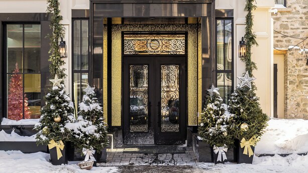 A hotel entrance with a snow-covered path, decorated with Christmas trees and garlands.