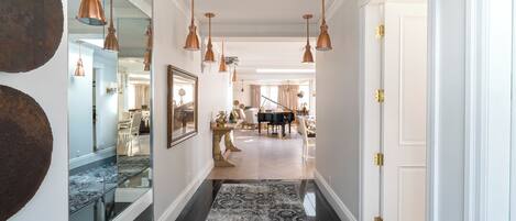 A hallway with a patterned rug, mirrored walls, and multiple hanging copper pendant lights.