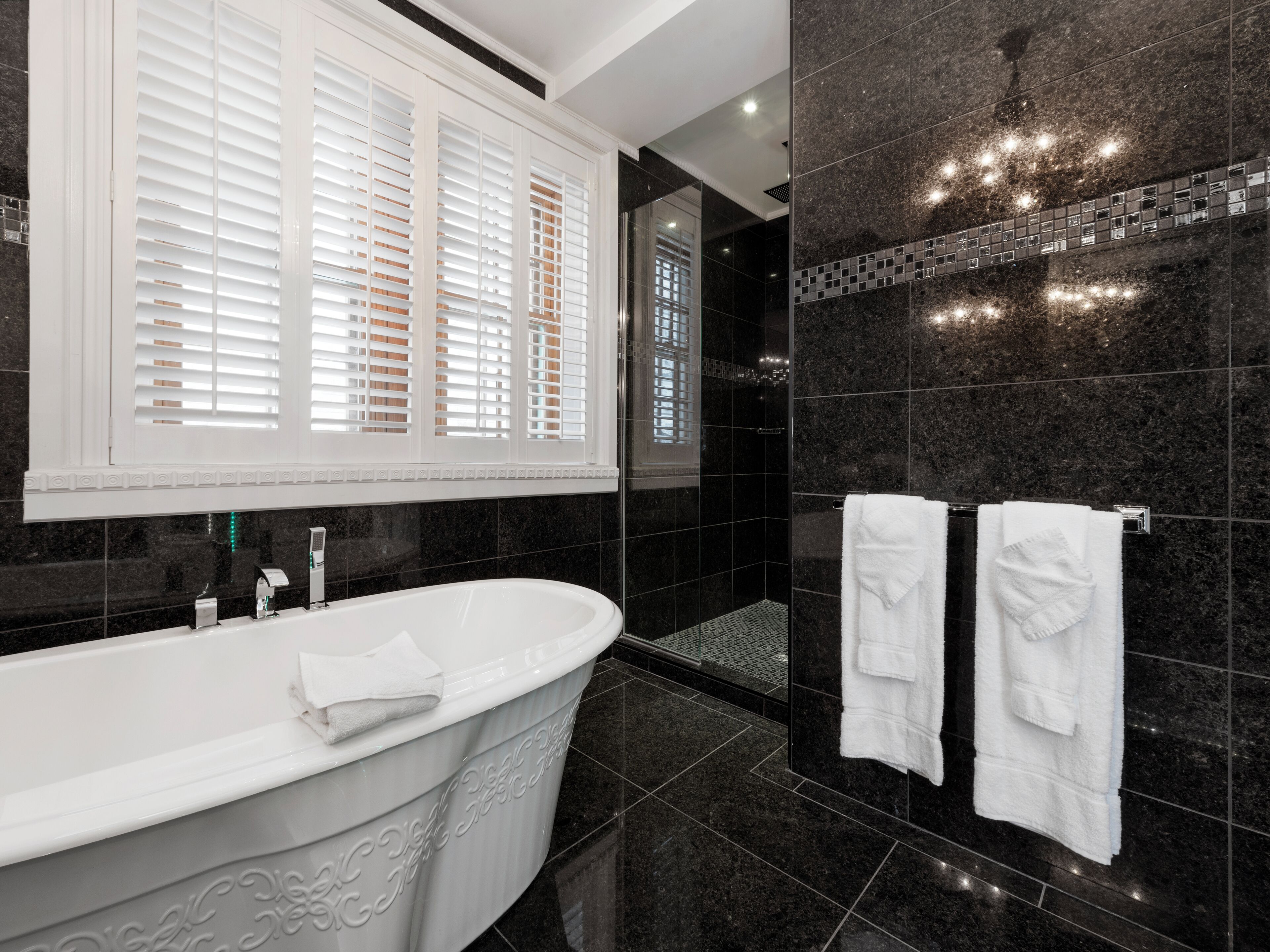 A modern bathroom with a freestanding bathtub, a large mirror, and a shower area.