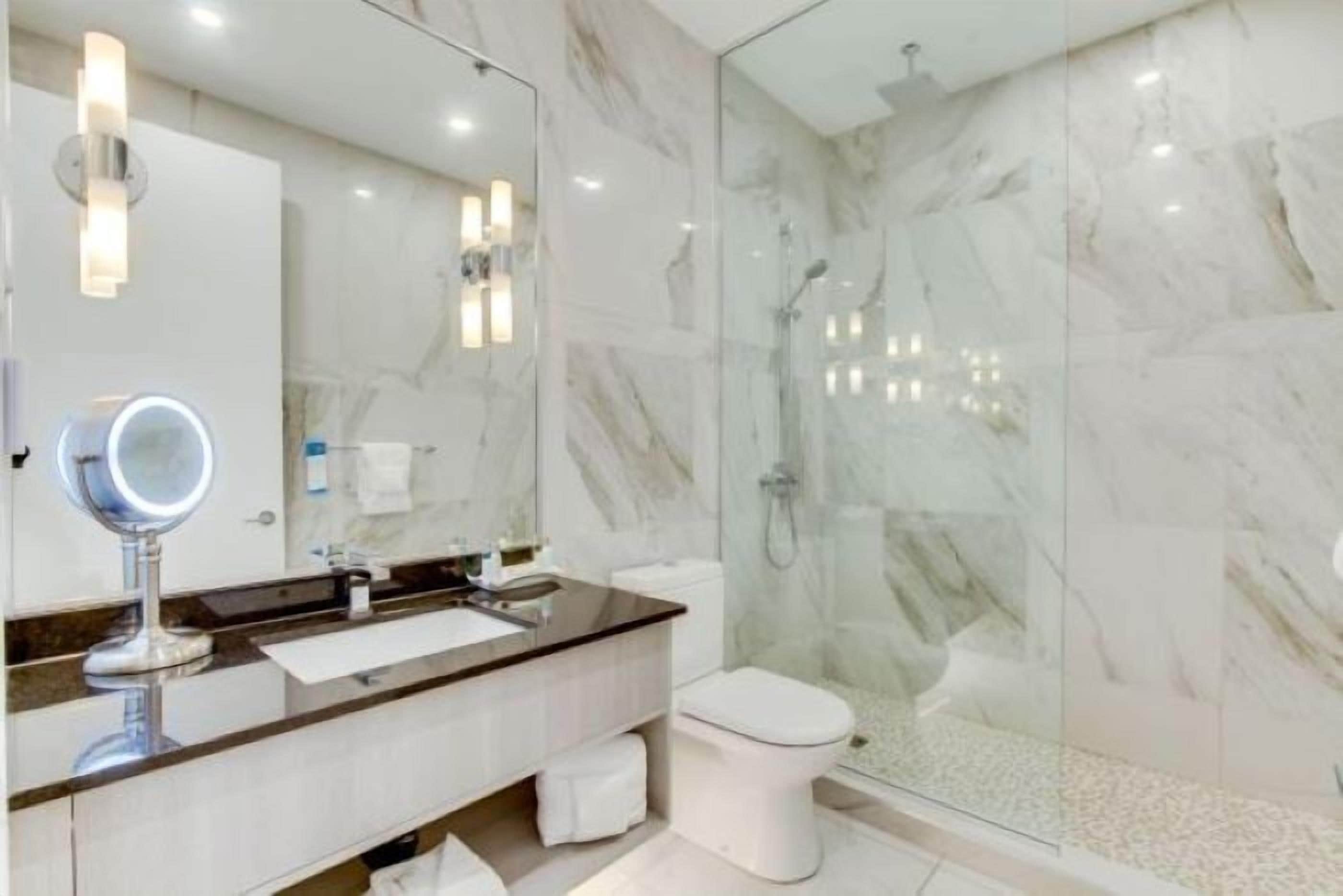 A modern bathroom with a marble shower, a glass-enclosed shower, and a vanity with a mirror.